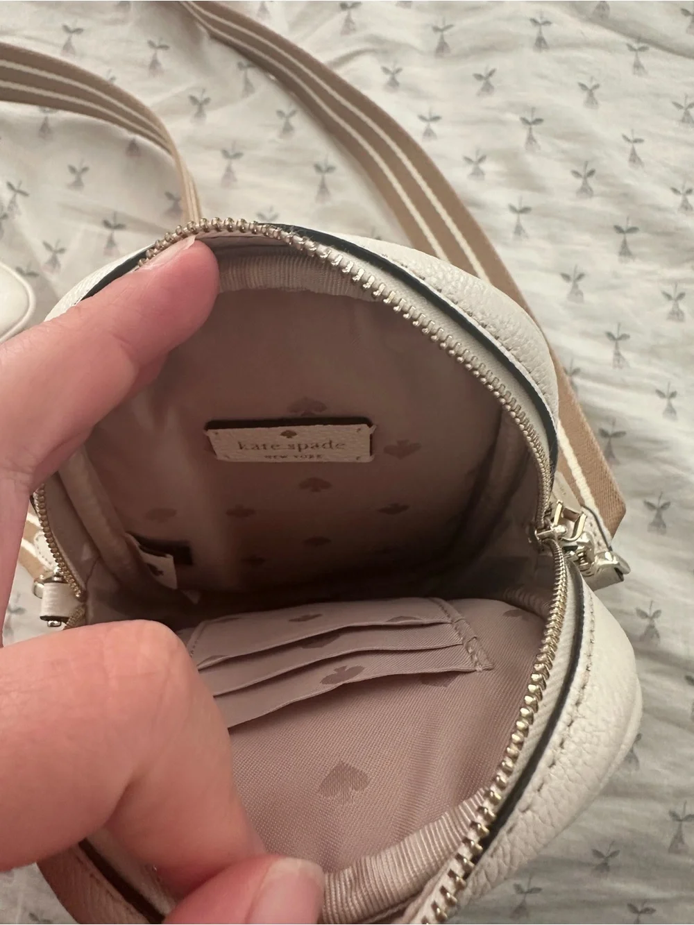 Kate Spade cream crossbody bag with tan striped strap and attached card holder